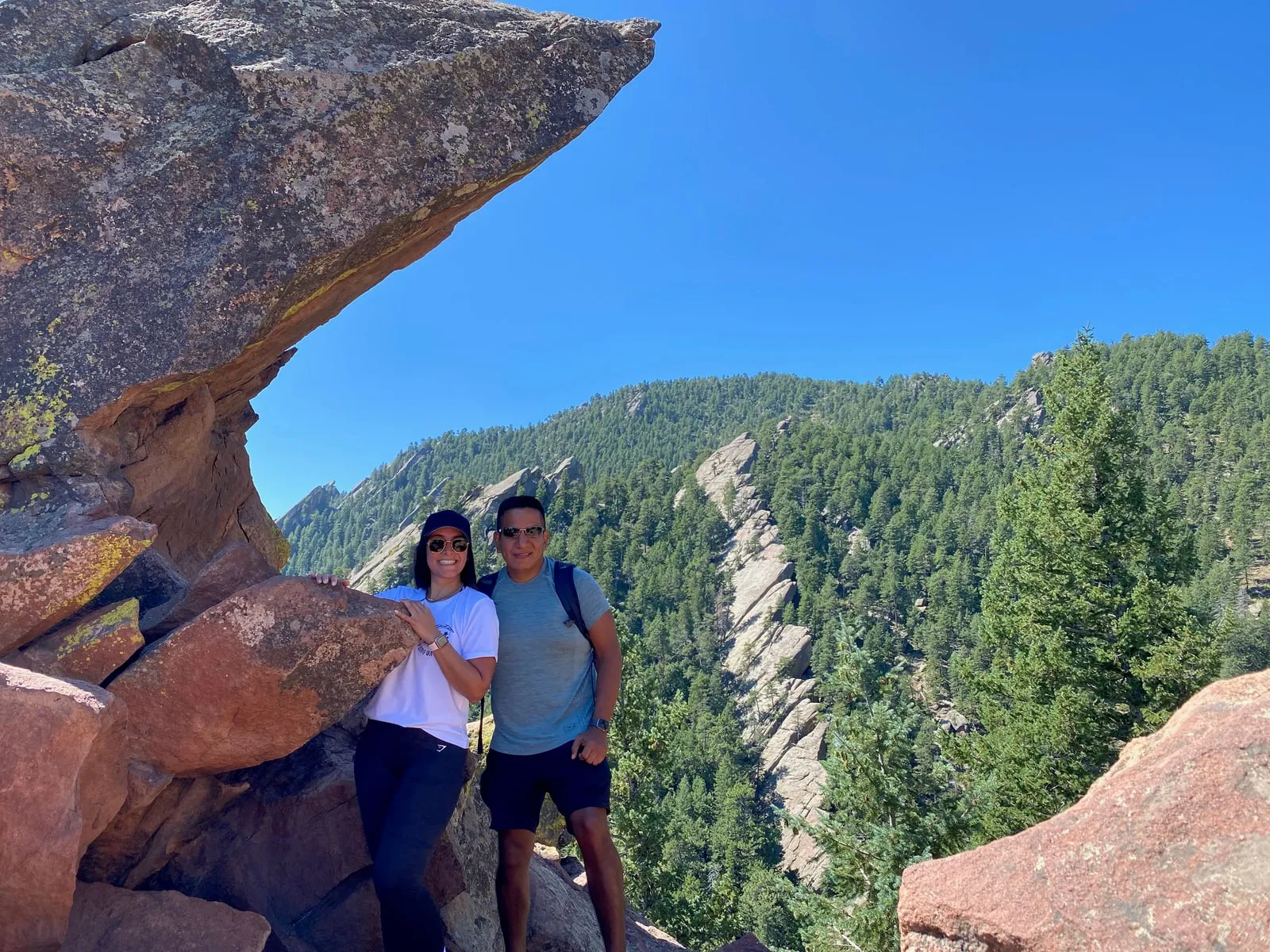 Katherine and Isaac on a rocky mountain lookout above a forested valley