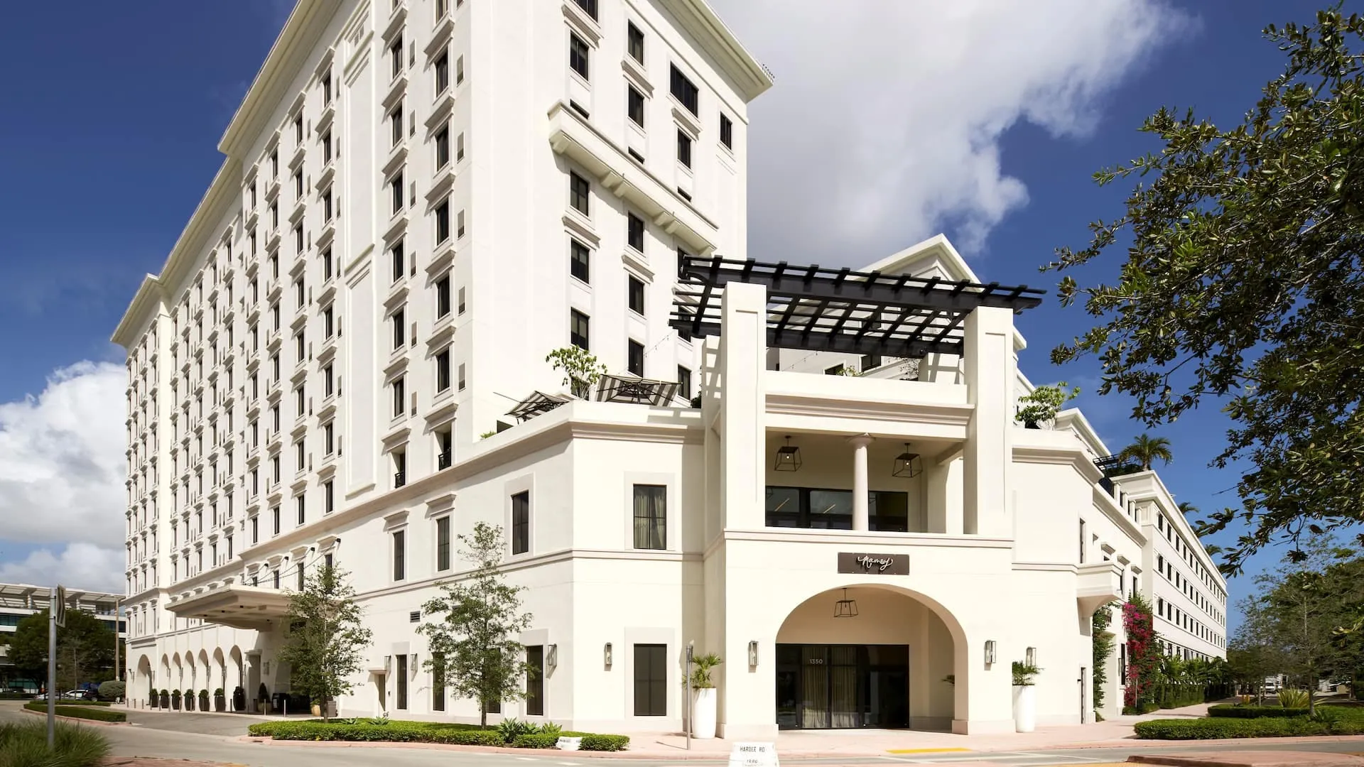 The white Mediterranean-style facade of Thesis Hotel in Coral Gables under a blue sky